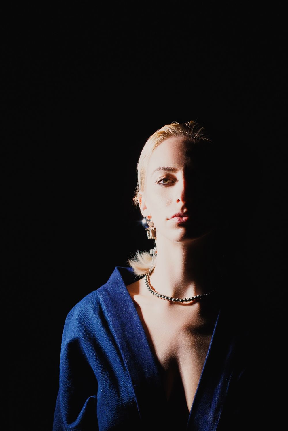 Stylistic portrait series in dark studio lighting showing dramatic angles of person in blue shirt against black background.
