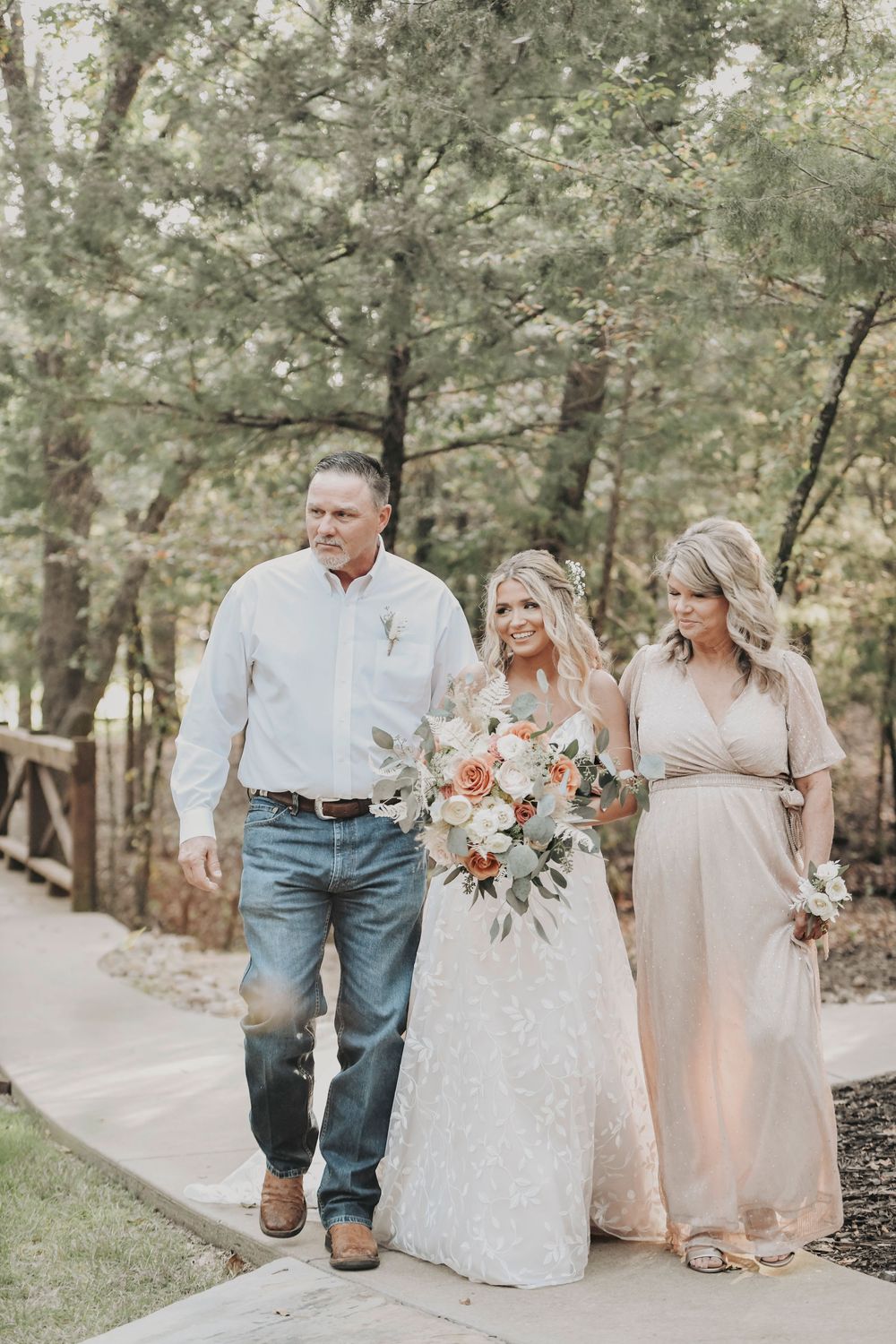 Bride walking down the aisle through oak grove at Whispering Oaks Wedding Venue