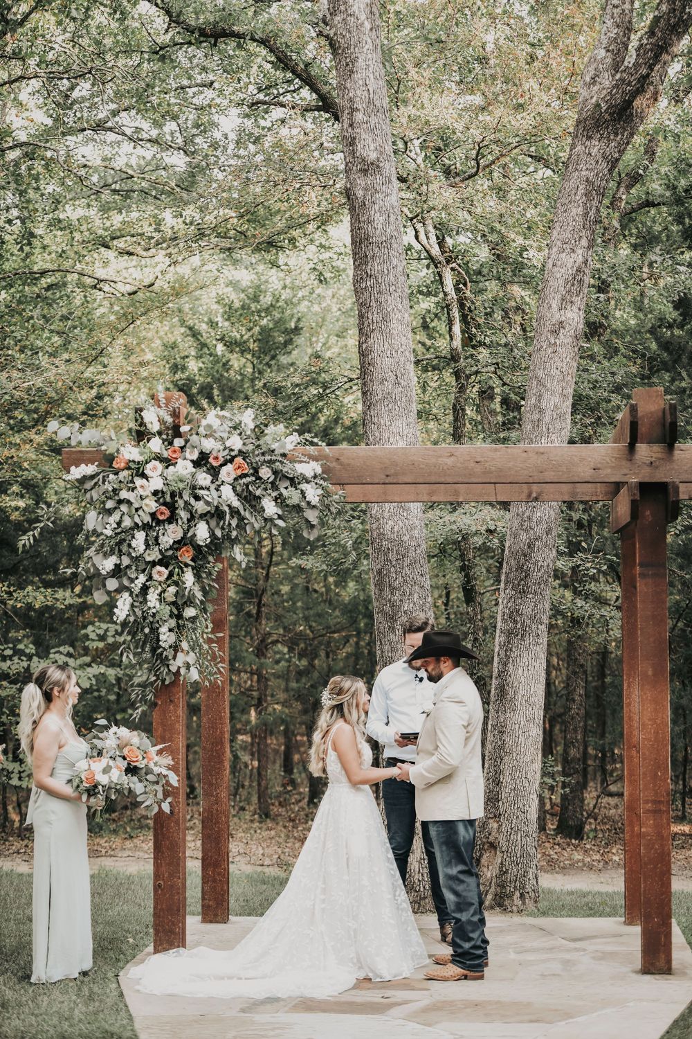 Bride and groom kissing at altar with dusty blue bridesmaids behind them