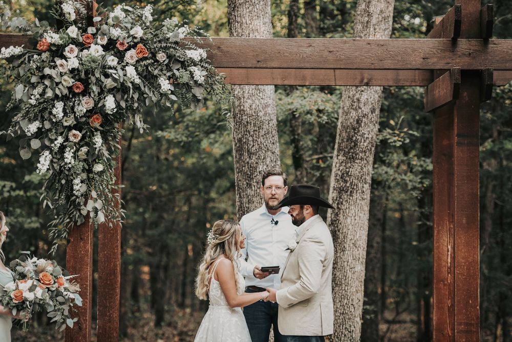 Couple exchanging rings beneath oak branches at Whispering Oaks