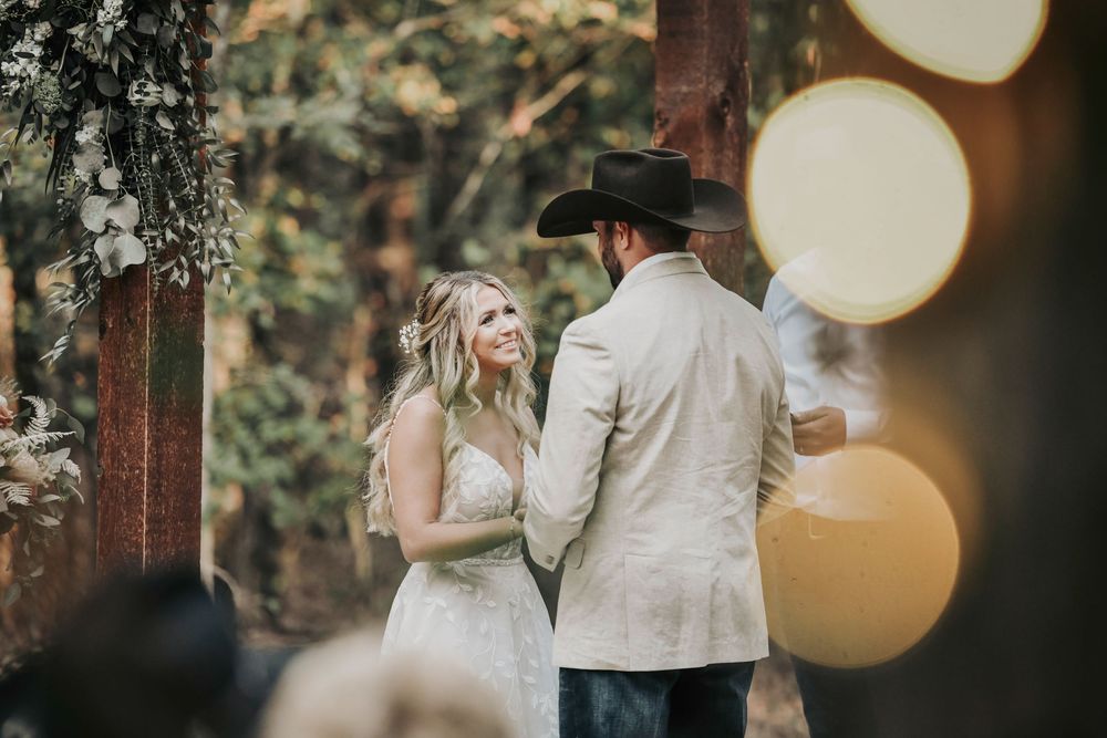 Rustic chic ceremony under Whispering Oaks trees with cowboy-booted groomsmen