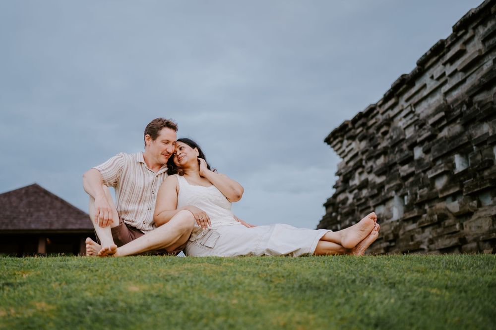A group relaxes together on a grassy hillside against a stone wall.