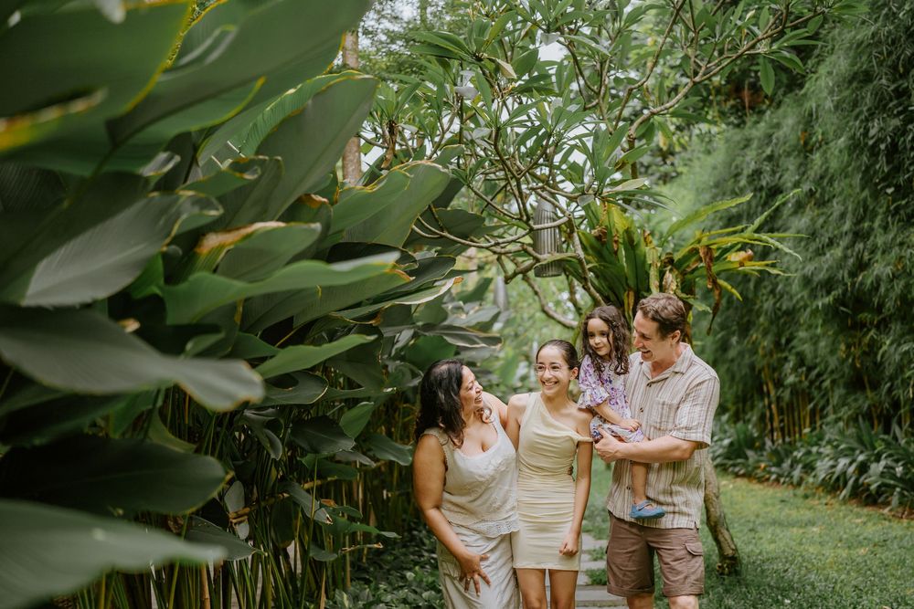A family shares tender moments together in a lush tropical garden setting.