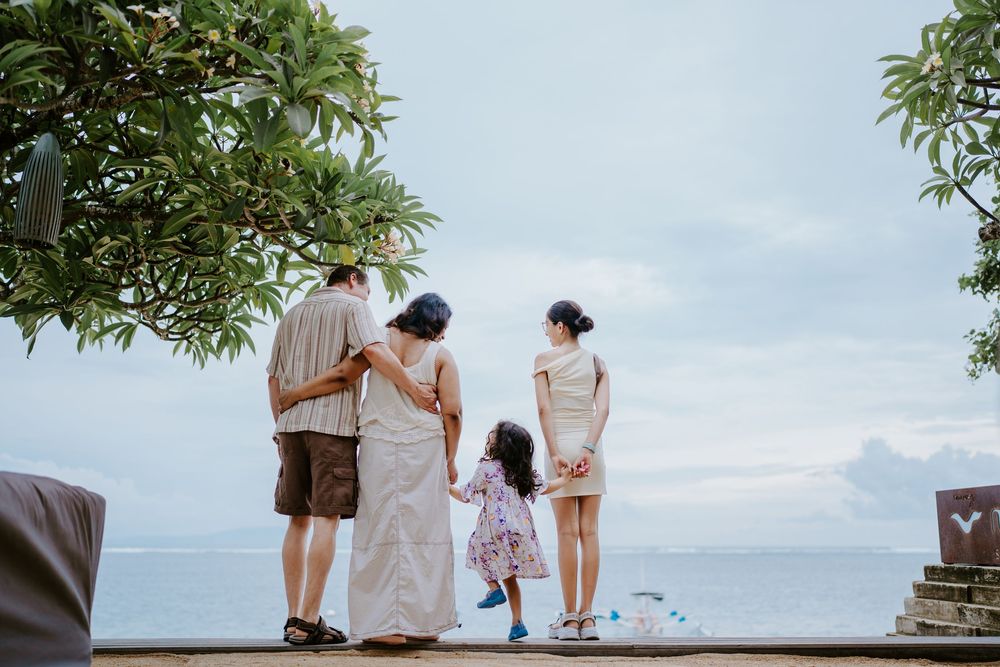 A family explores an outdoor path under tropical trees on a sunny day.