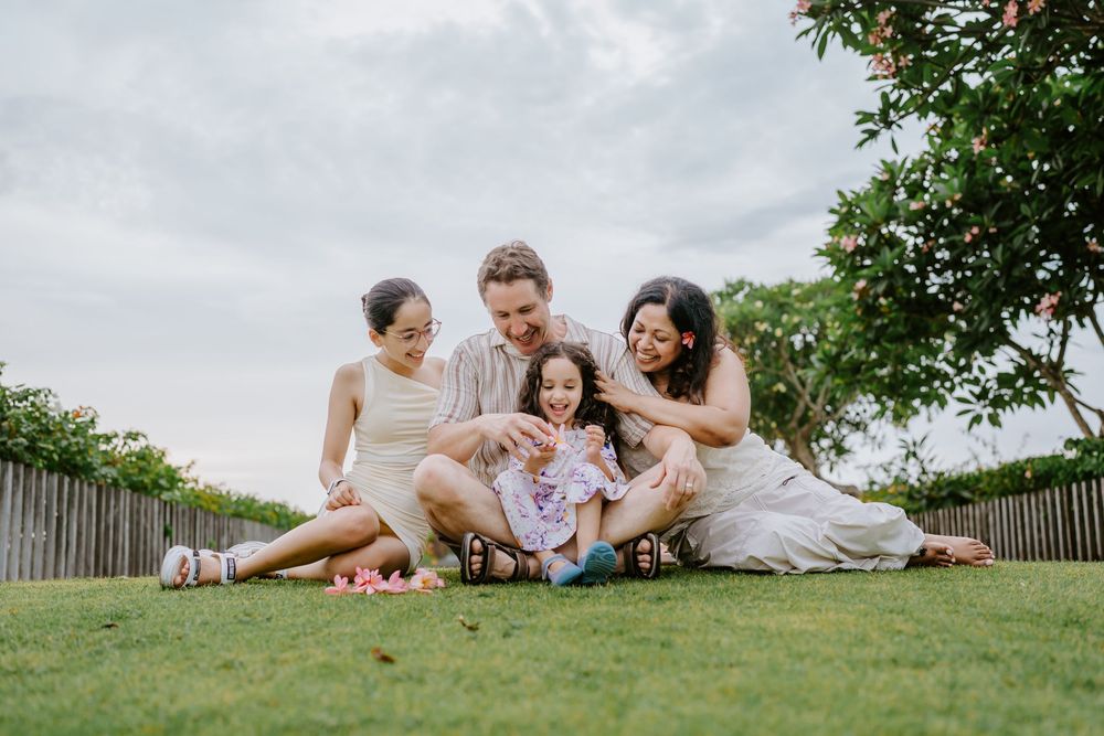 A family shares intimate moments while relaxing on a grassy slope outdoors.