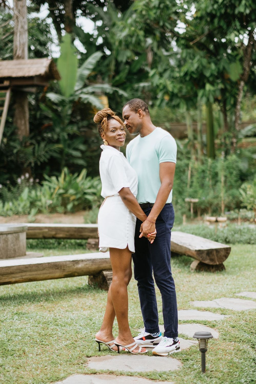 A couple shares an intimate moment in a lush garden setting.