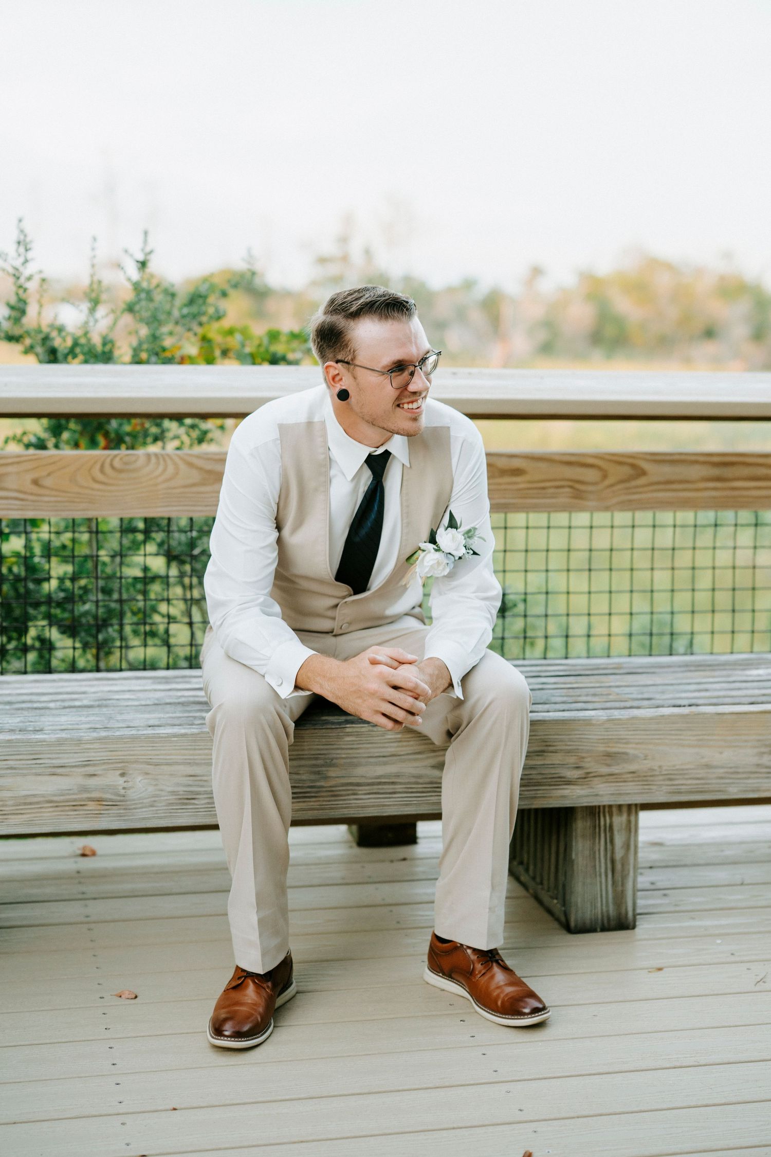 Four panel sequence showing person sitting on wooden deck bench wearing light colored suit and brown shoes.