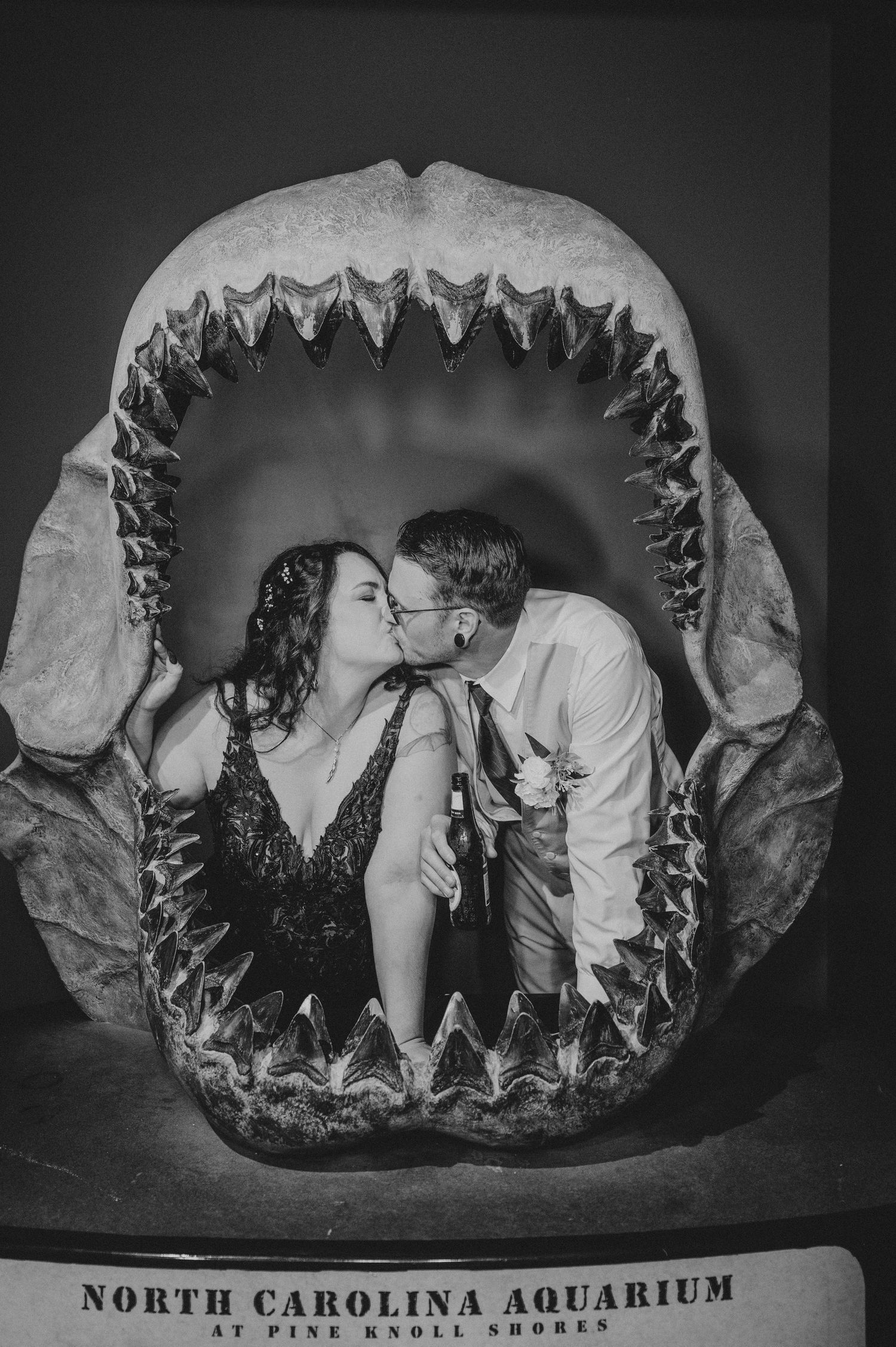 Three black and white photos show a couple posing inside giant shark jaw displays at an aquarium in North Carolina.