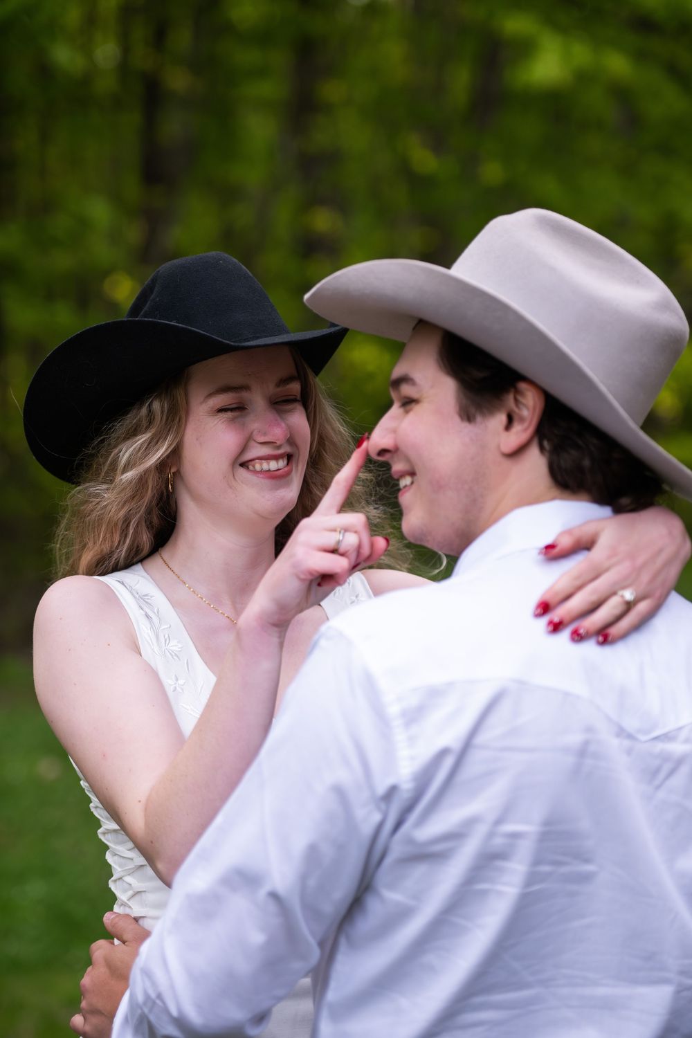 A romantic outdoor photoshoot with newlyweds embracing and laughing in a rustic countryside setting.