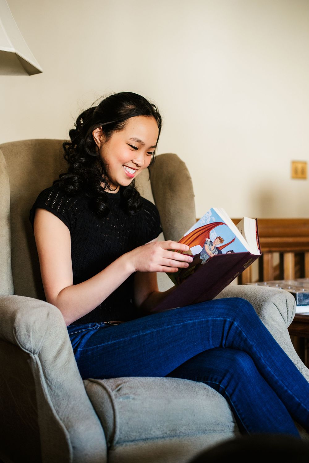 Highschool senior reads a book in the comfort of her home for senior session photos