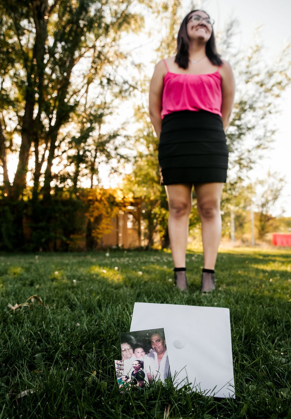 Focus is on Senior's graduation cap with an image of her family while she is in the background smiling