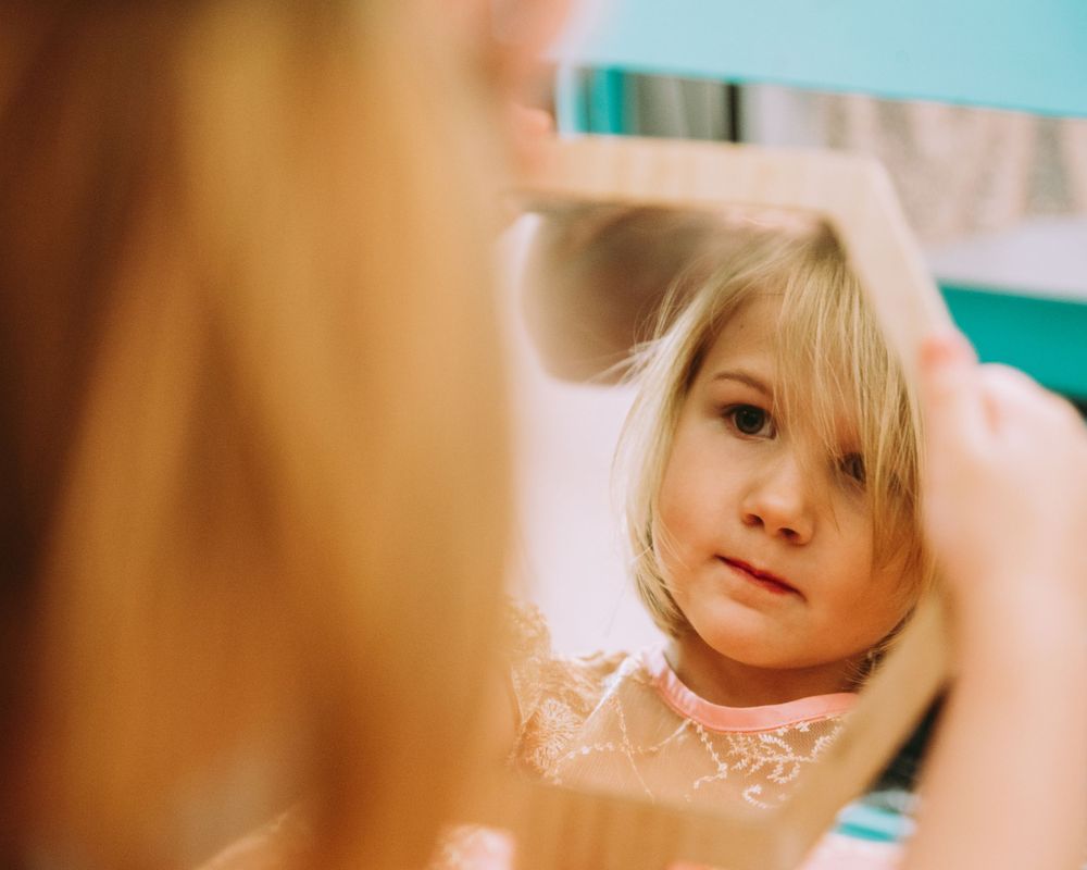 Birthday girl looks at her princess makeup in a mirror