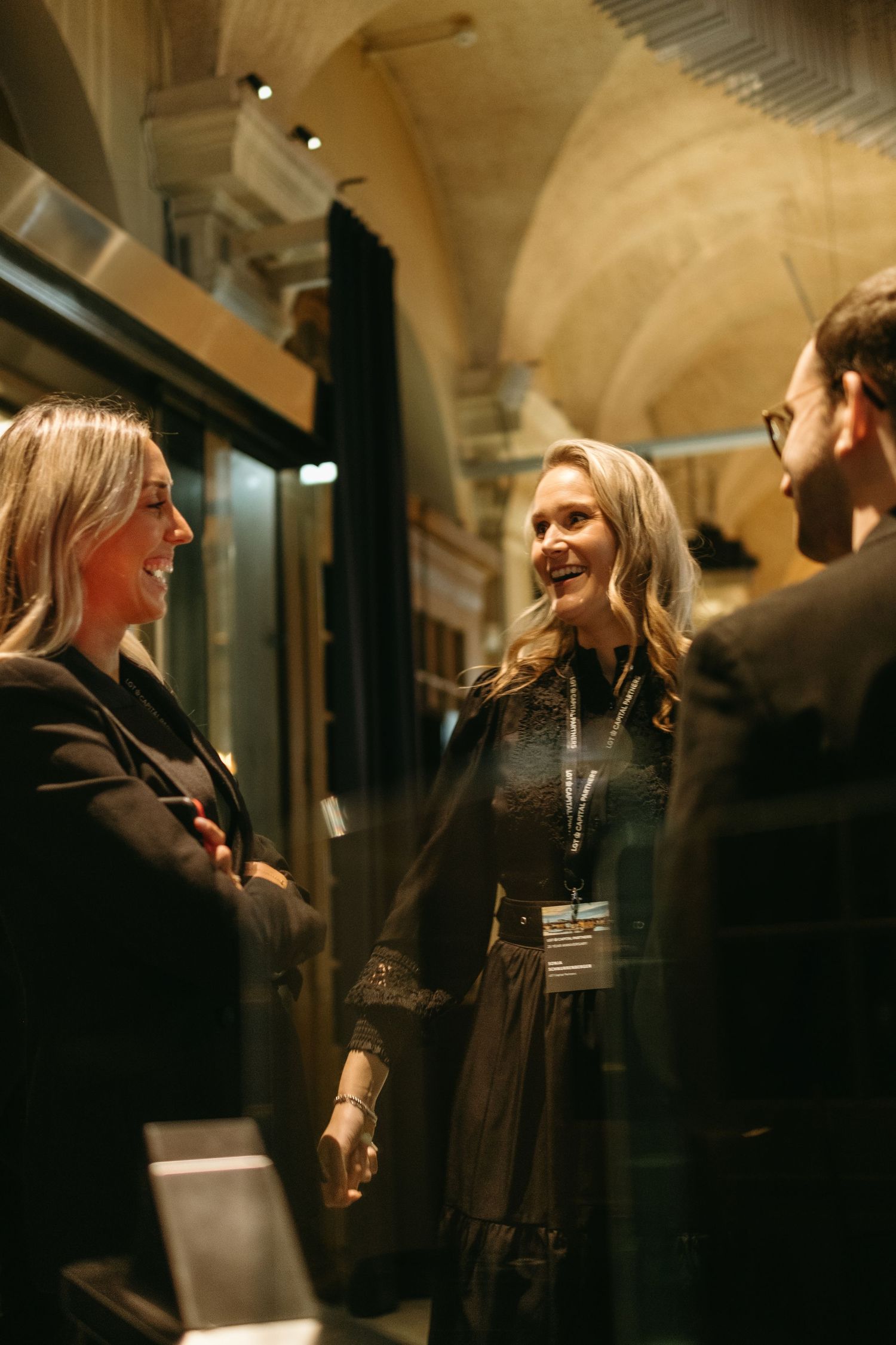 two women laughing and talking to a man while being captured during corporate event photoshoot in Stockholm
