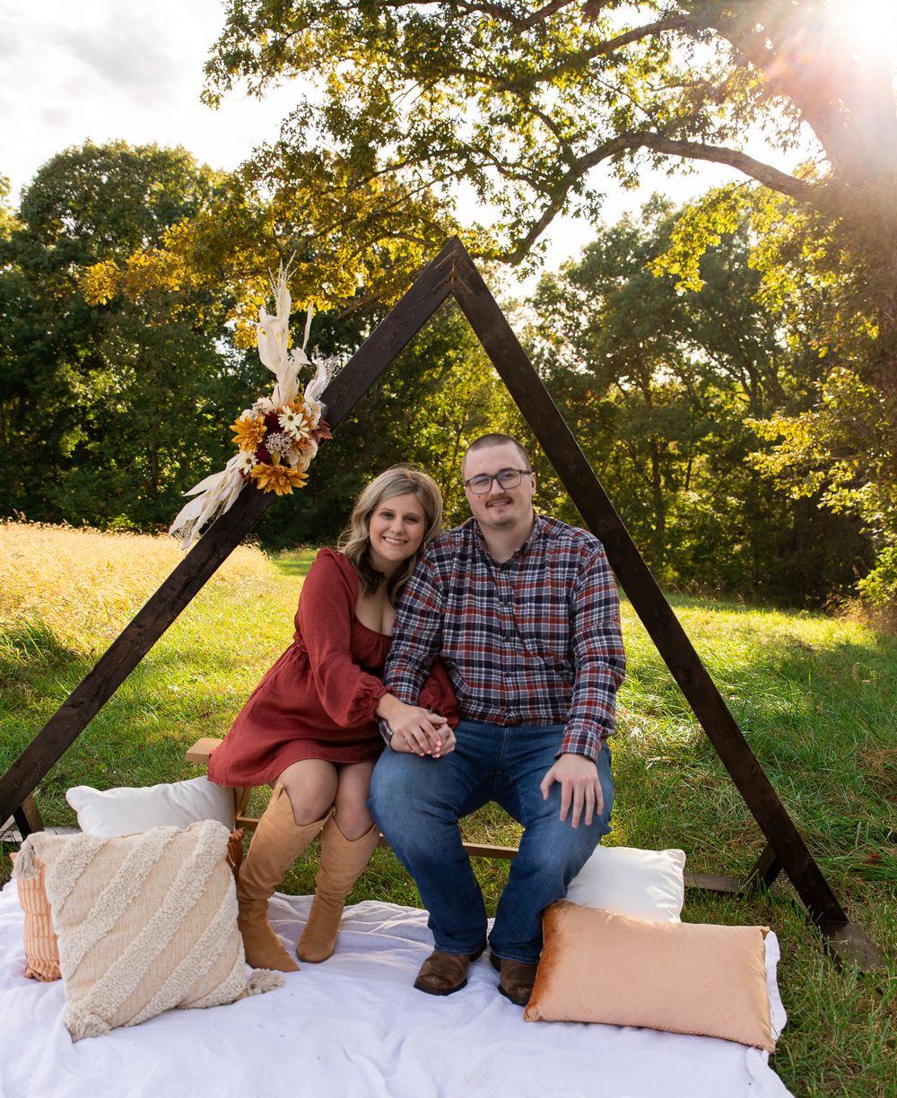Outdoor photo session setup with wooden frame and white blanket in golden sunlight.