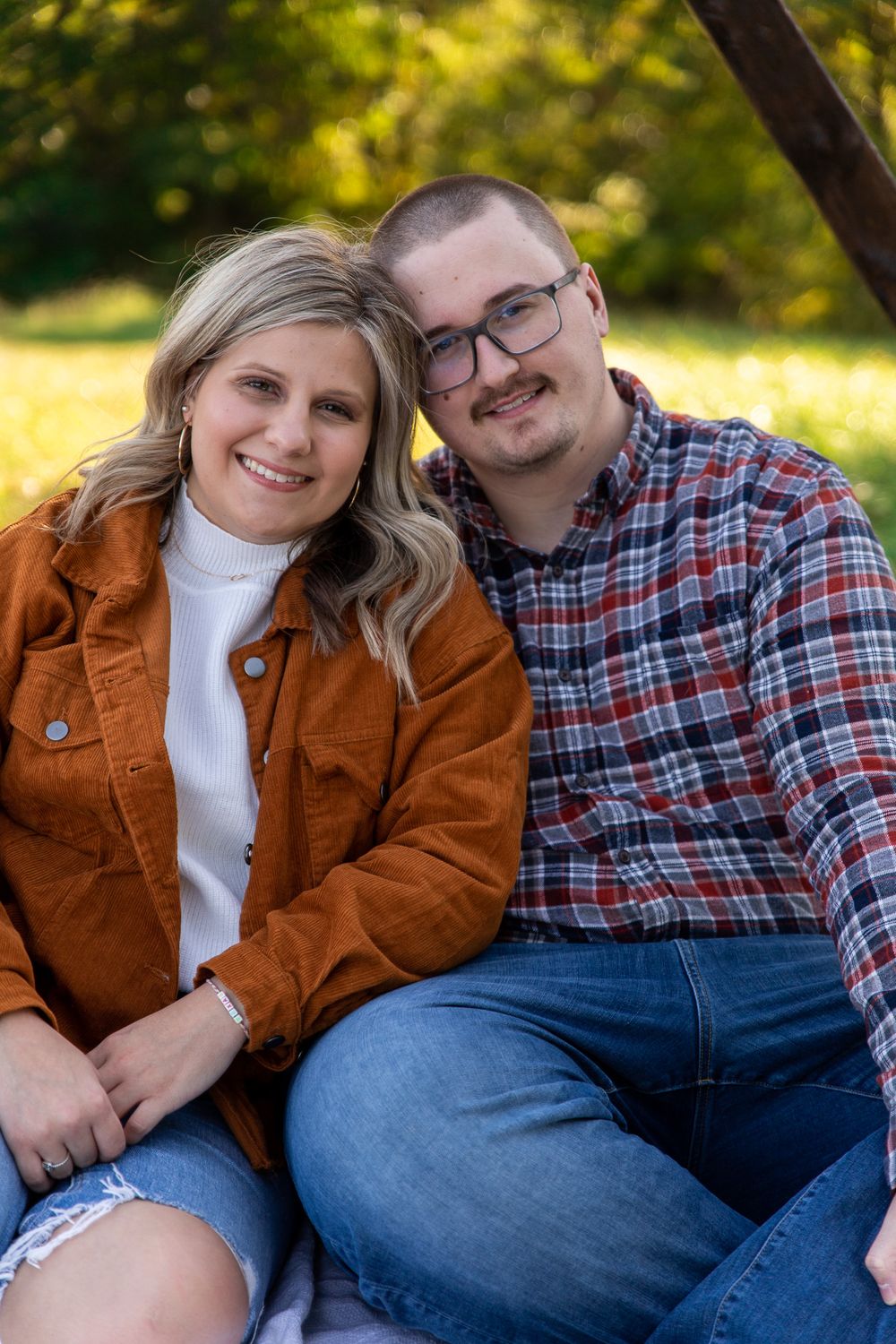 Couple in casual fall attire sharing intimate moments during outdoor photoshoot.