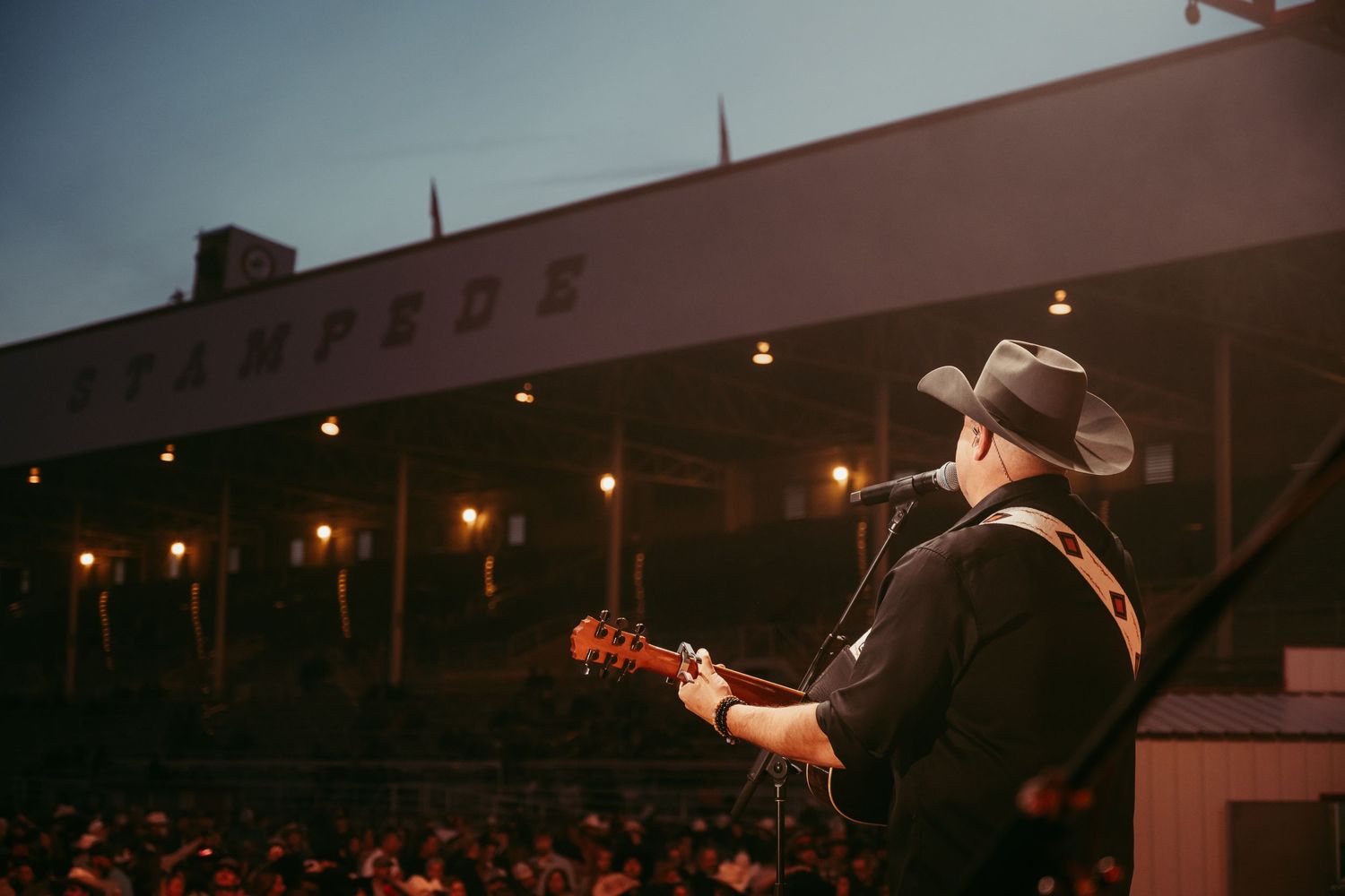 Country musician performing on stage with guitar at night.
