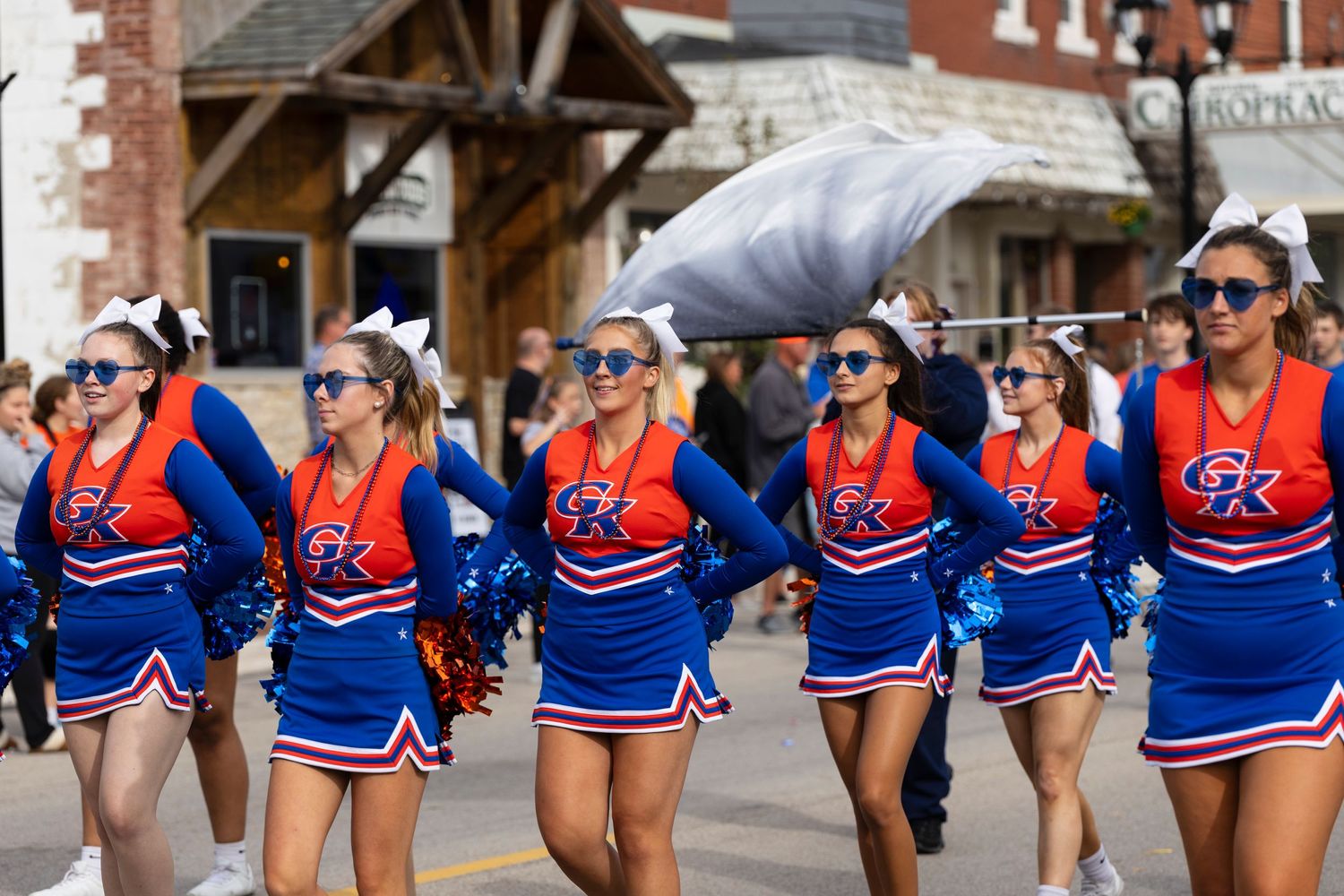 Cheerleaders in bright blue and red uniforms perform during a parade on a city street.
