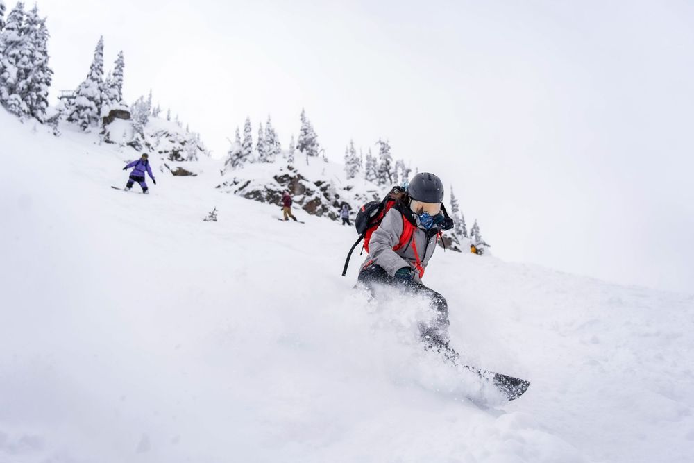 Two snowboarders riding down a slope