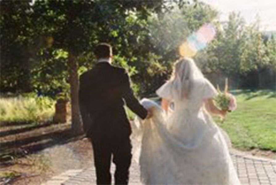 Bride and groom walk away from camera in a candid film photo in a Utah Garden wedding venue.