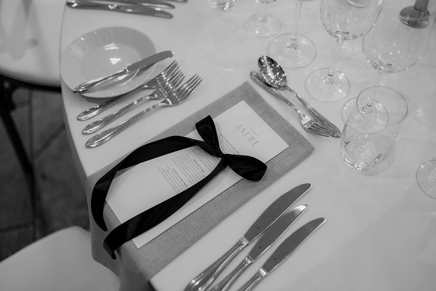 Black and white table setting with elegant place cards and silverware at a formal event.