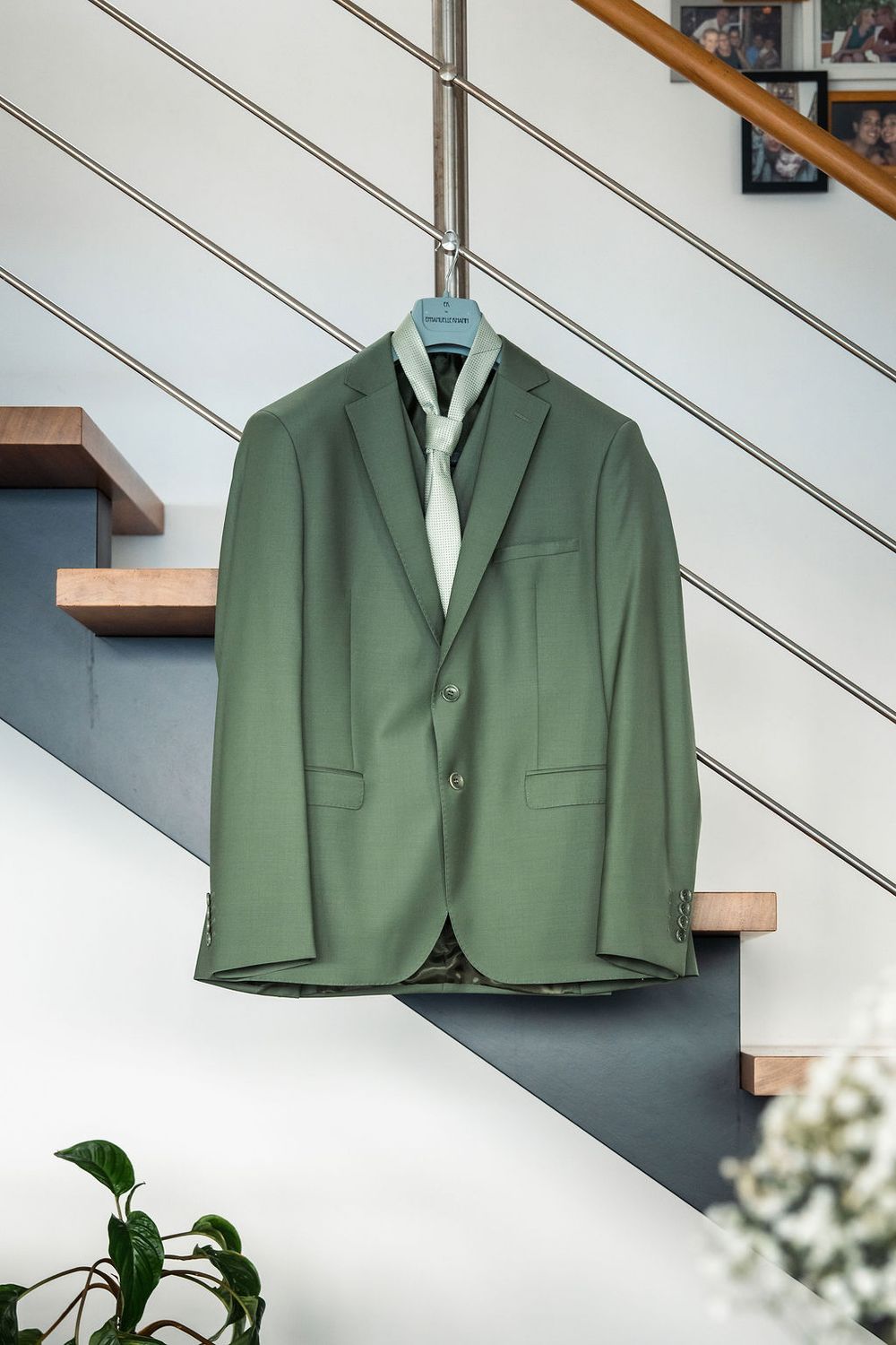 Green men's suit jacket hanging on staircase railing with matching tie for wedding day.