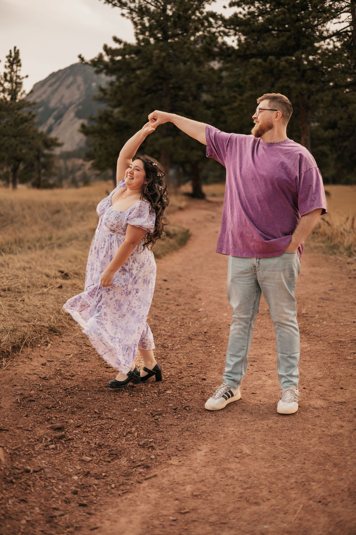 Couple dancing on a dirt path with mountains and pine trees in the background | Couple Photos in Boulder, Colorado