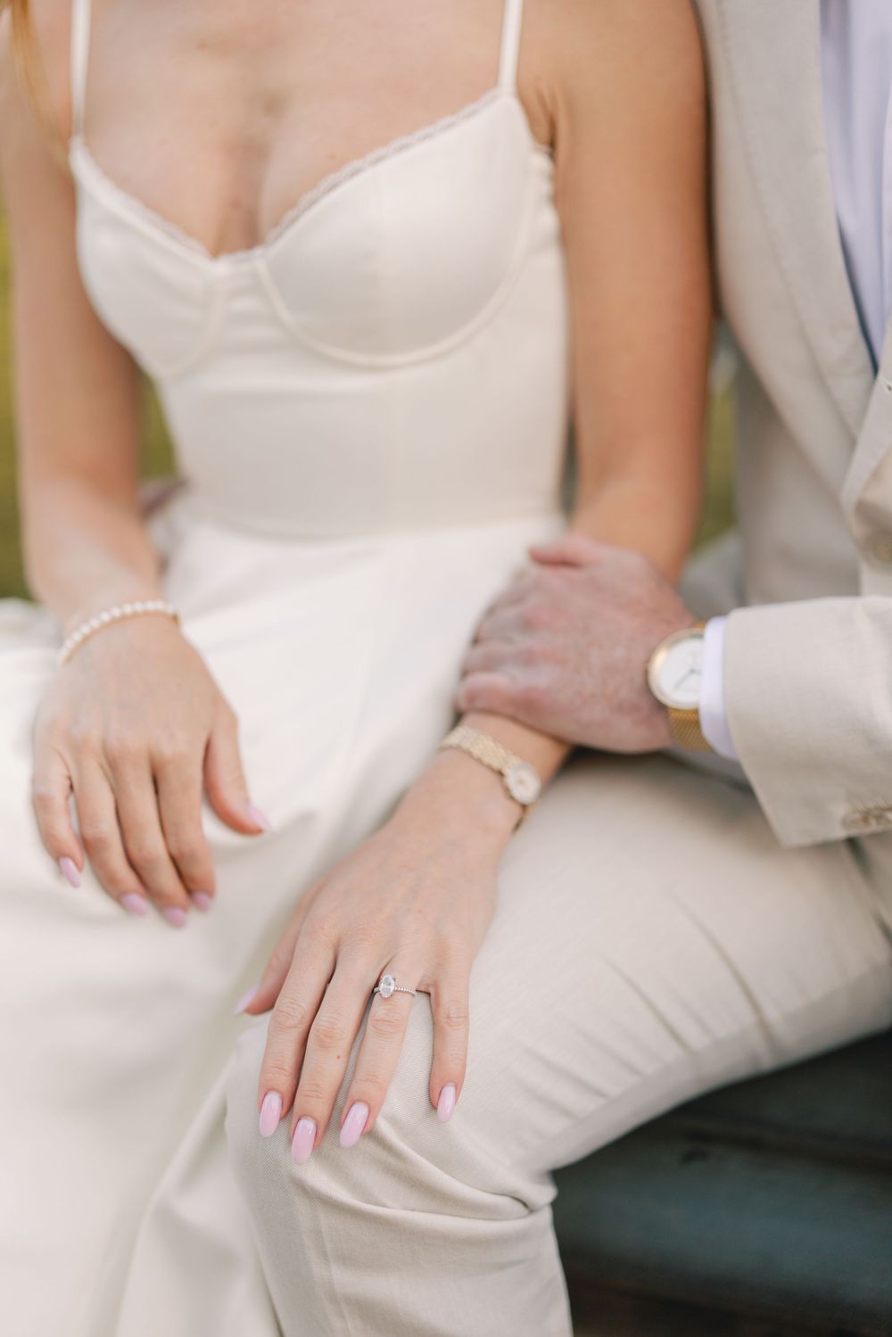 Close-up of bride and groom hands showing diamond engagement ring, pearl bracelet, and wedding watch on wedding day.
