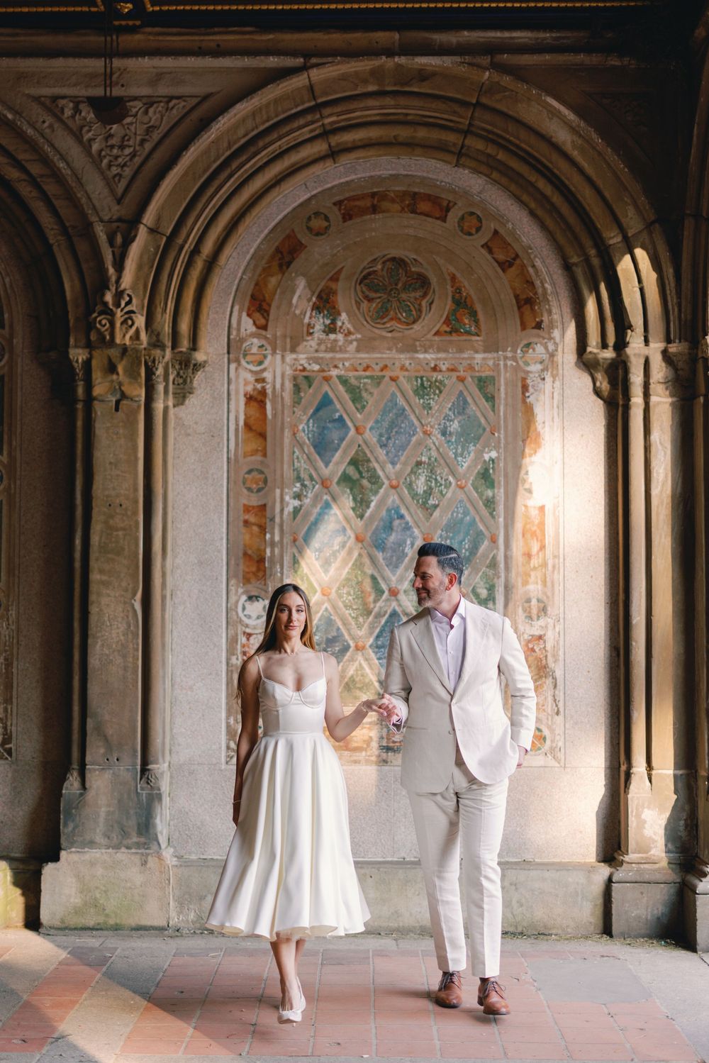 Bride and groom holding hands in Bethesda Terrace arcade, Central Park, NYC.