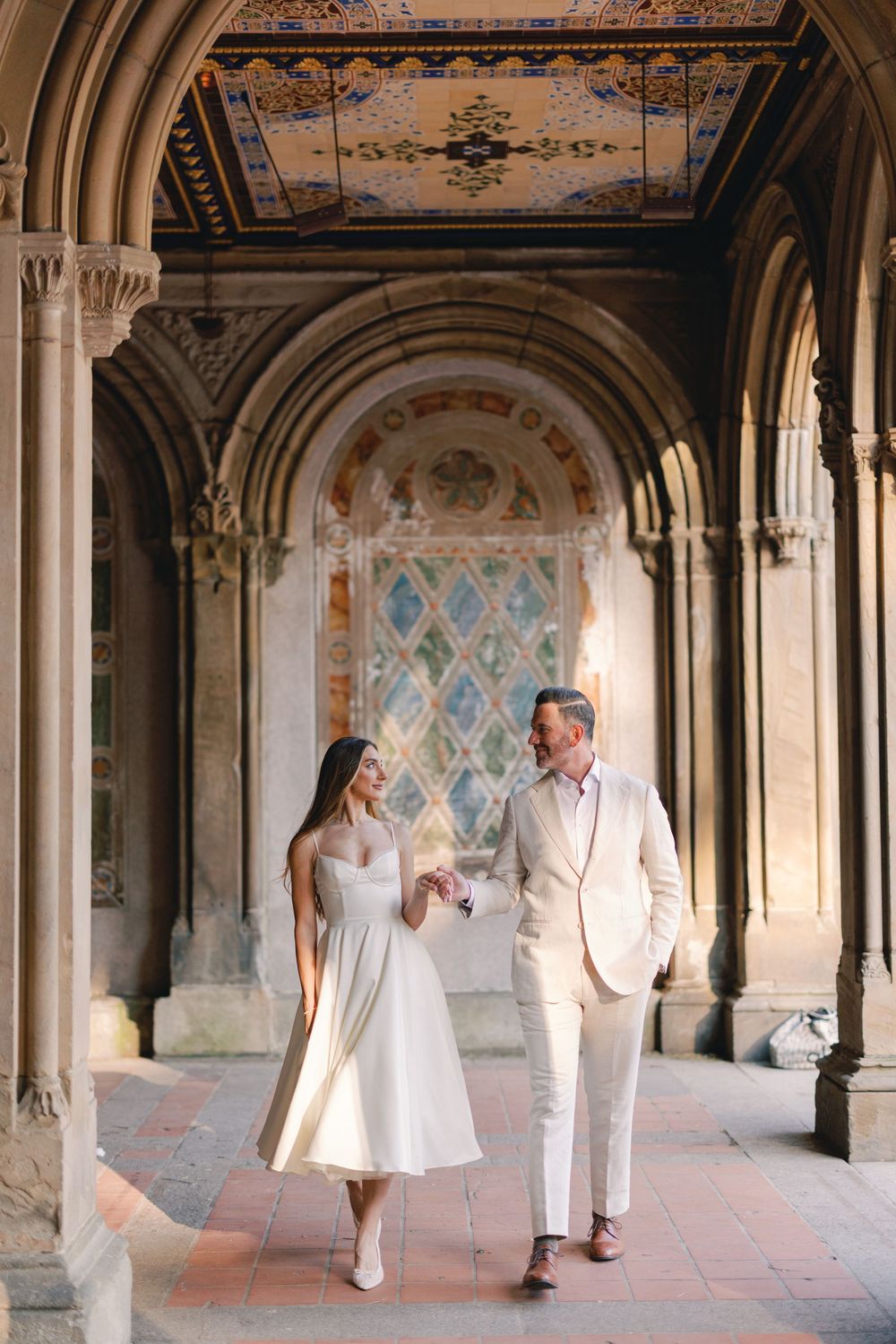 Wedding couple walking through ornate Bethesda Terrace arcade in Central Park, NYC.