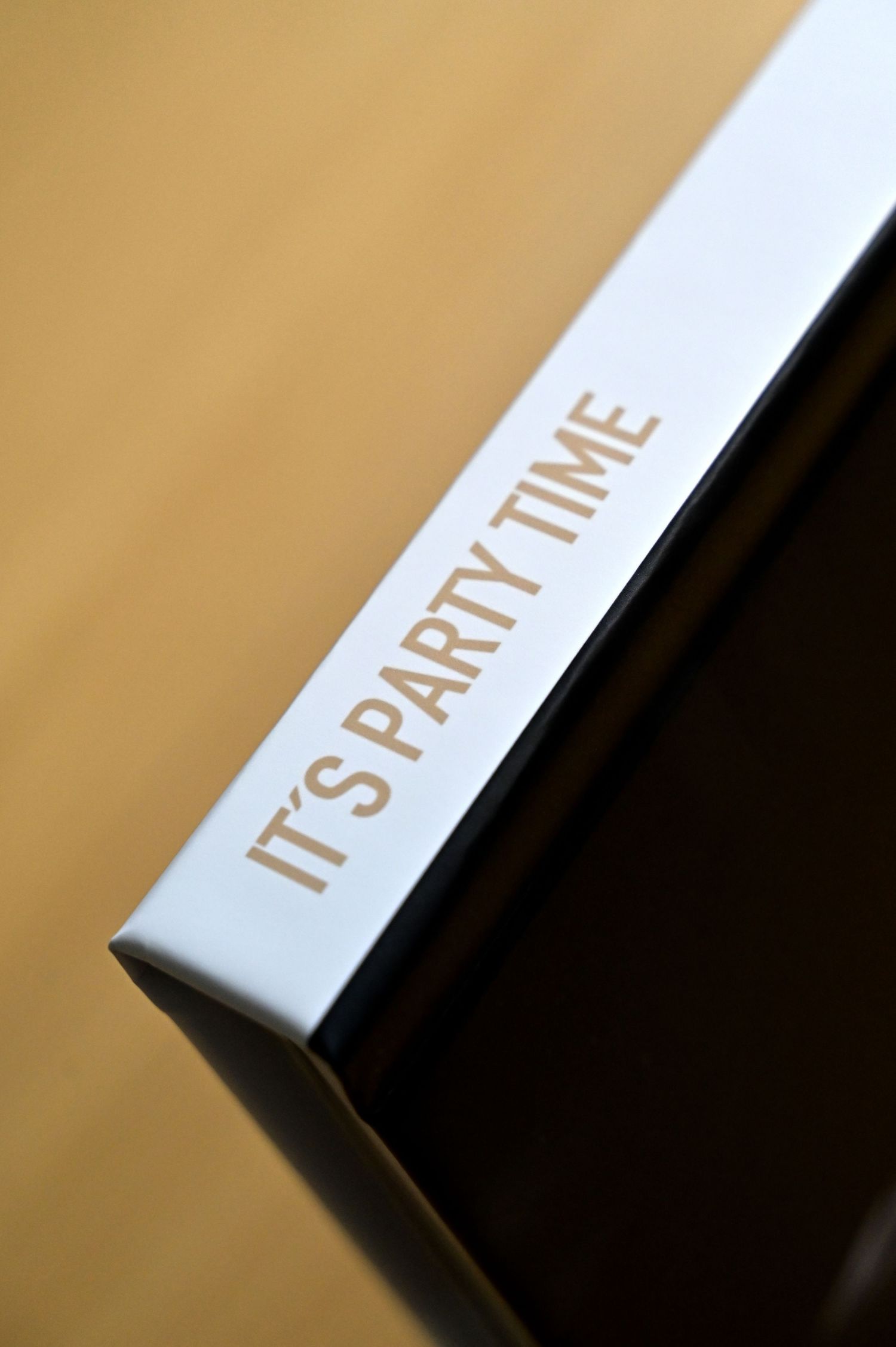 Close-up of Its Party Time text embossed in gold on white book spine against dark background.