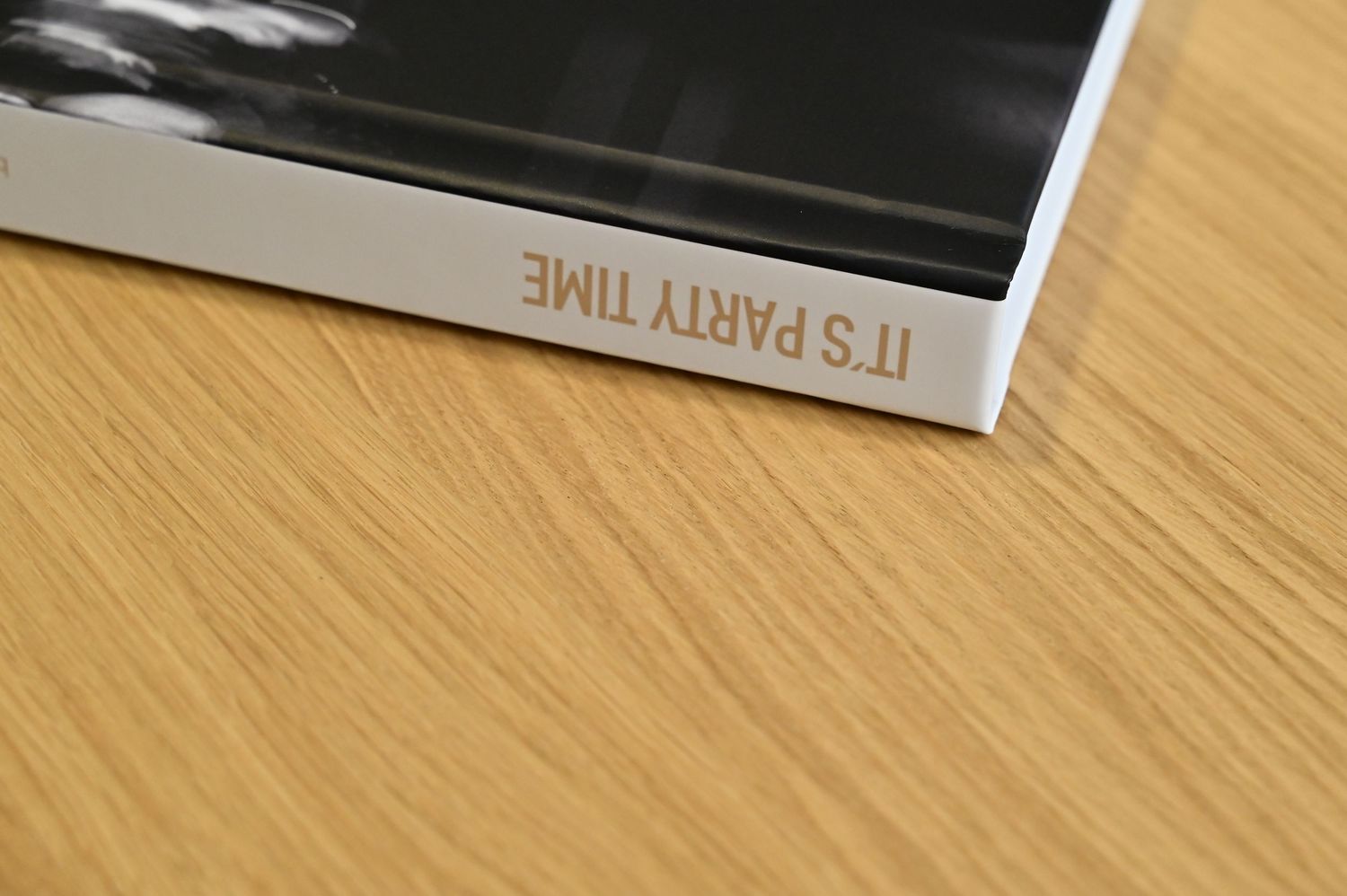 Gold foil text reading Its Party Time on the white spine of a hardcover photo book.
