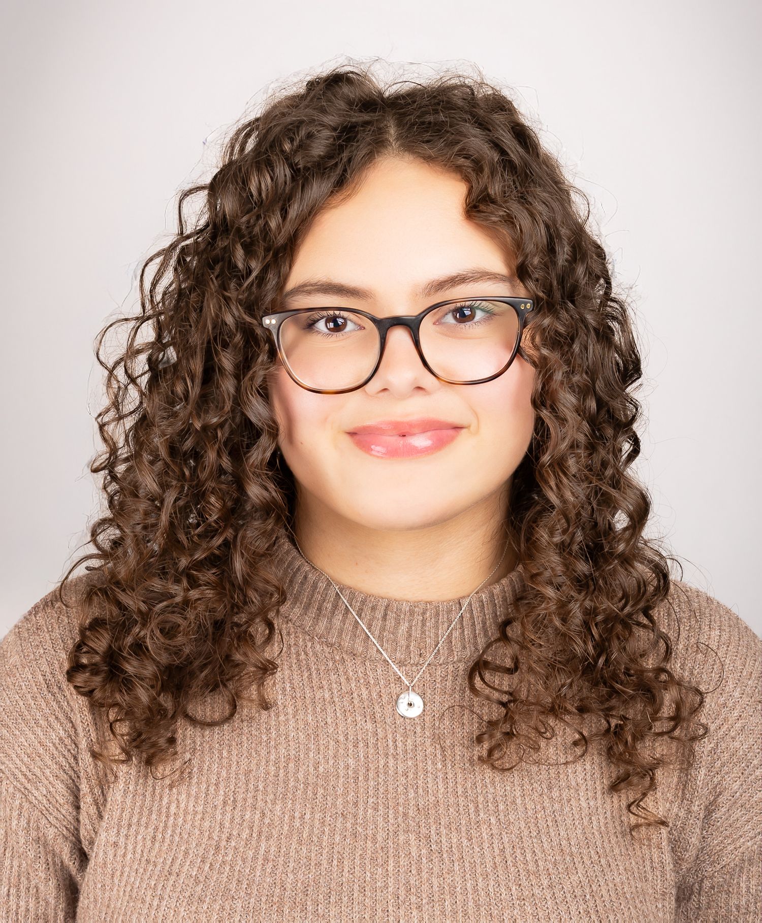 Image of a girl with glasses smiling at the camera, front shot