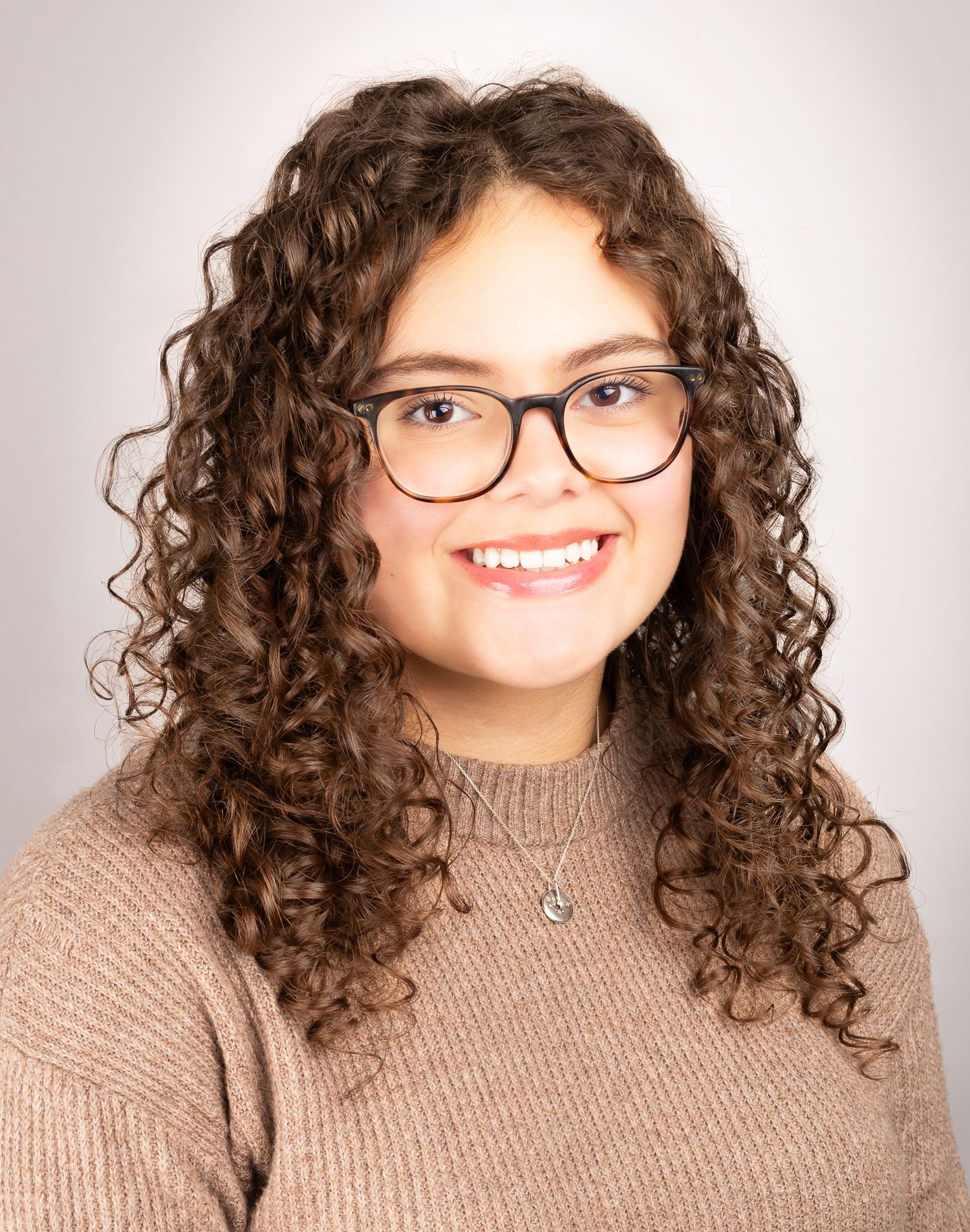 Image of a girl with glasses smiling at the camera with teeth, side angle shot