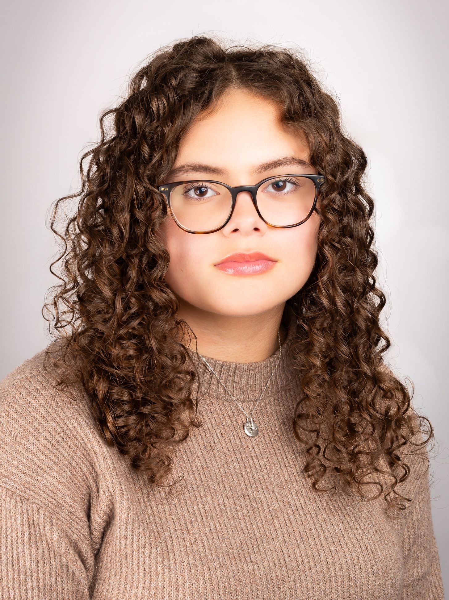 Image of a girl with glasses looking at the camera with a neutral expression, front shot