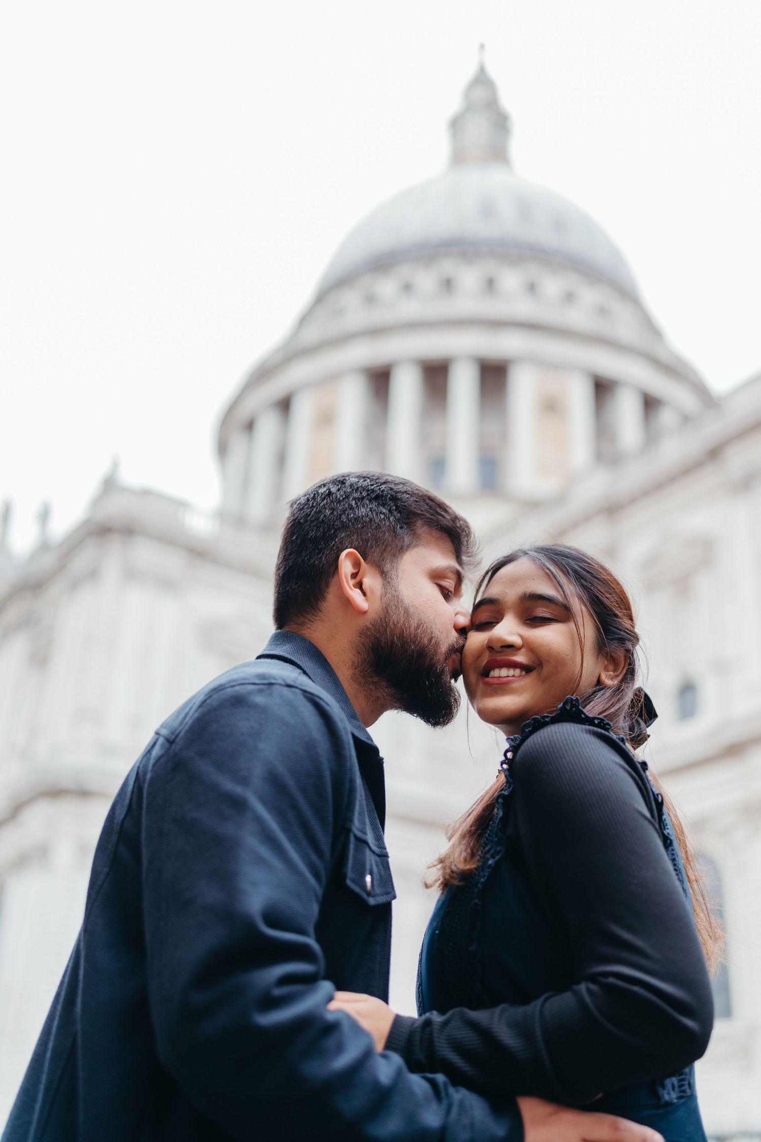 Indian couple walking together, bride in red saree and groom in black suit.