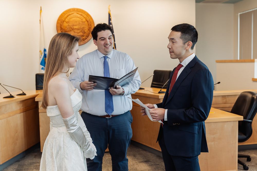 Couple exchanging vows with officiant in formal courthouse civil wedding ceremony setting.