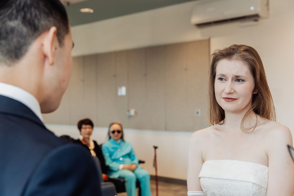 A bride in a strapless dress exchanges vows with a groom during an intimate wedding ceremony.