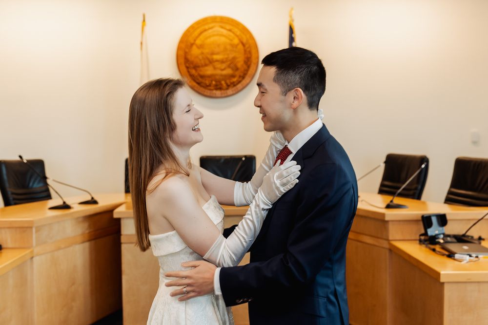 Newlywed couple sharing a romantic embrace in a courthouse courtroom after their civil wedding ceremony.