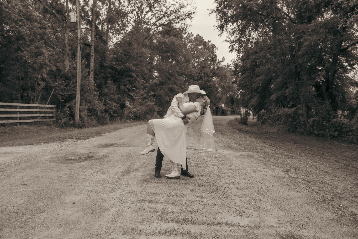 Bride and groom sharing first kiss at outdoor wedding ceremony surrounded by seated guests.