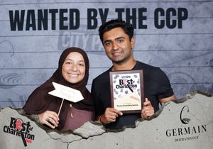 Couple holding Best of Charleston award at Germain Dermatology CCP wanted photo booth.