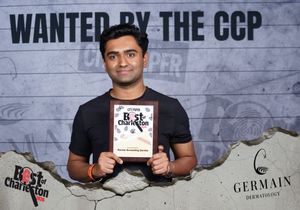 Man holding Best of Charleston award plaque in front of Wanted by the CCP event backdrop.