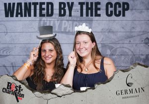 Two women wearing novelty hats smile at Best of Charleston Wanted by the CCP photo booth.
