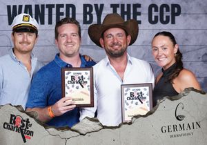 Four people displaying Best of Charleston awards at CCP wanted photo booth with fun hats.