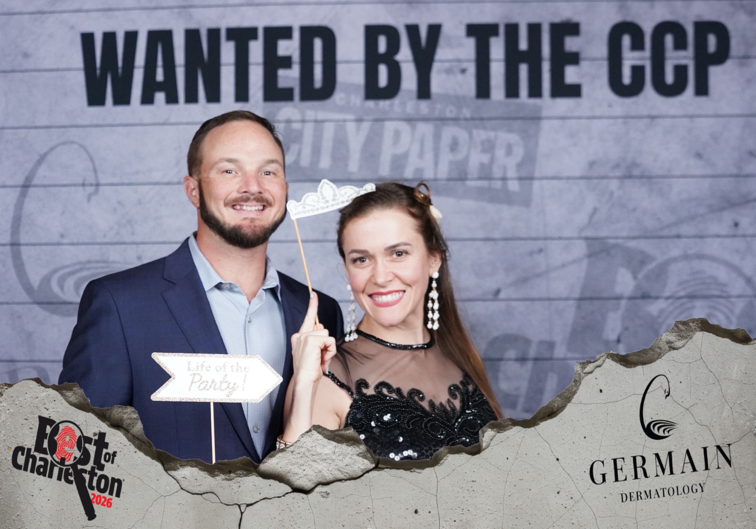 Smiling couple poses with directional sign prop at Best of Charleston CCP event photo booth.