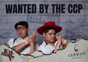 Two men pose under a Wanted by the CCP City Paper sign at a Best of Charleston event sponsored by Germain Dermatology.