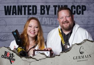 A woman and man smile under a Wanted by the CCP sign at a Best of Charleston event sponsored by Germain Dermatology.