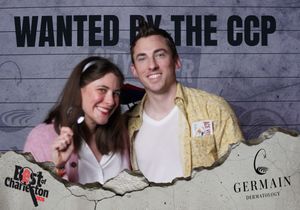Couple smiles at Best of Charleston photo booth with Wanted by the CCP backdrop and Germain Dermatology logo.