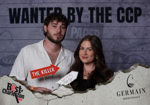 Young couple posing at Wanted by the CCP Best of Charleston event, man holding The Killer sign.