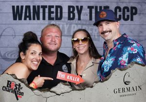 Four friends pose at Best of Charleston CCP wanted photo booth, one holding The Killer sign.