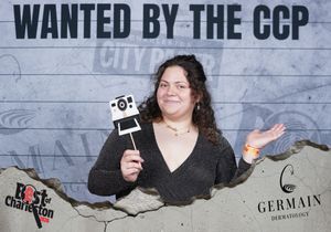 Woman smiling and holding a camera prop at Wanted by the CCP Best of Charleston event.